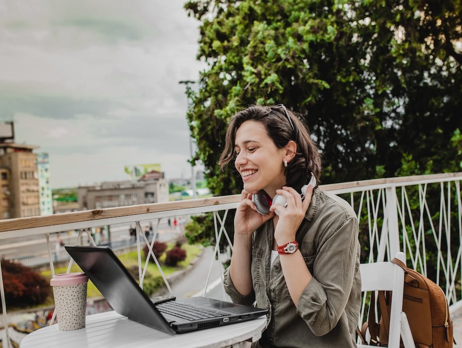 A young woman is sitting outside and having a video call