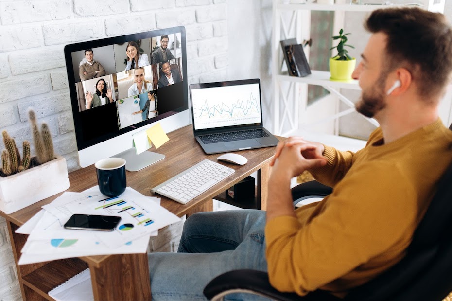 Health plan payer employee sitting at a desk while working remotely and attending a video conference with a secure communications platform