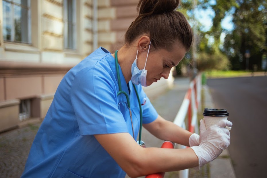 Healthcare worker holding coffee on a break at work looking stressed out