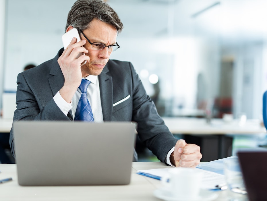 Insurance employee talking on cell phone while reading reports in the office.