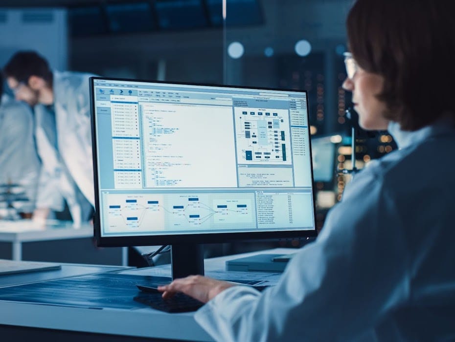 Employee within the pharmaceutical sector sits at a computer with his screen easily visible, putting the company's intellectual property at risk.