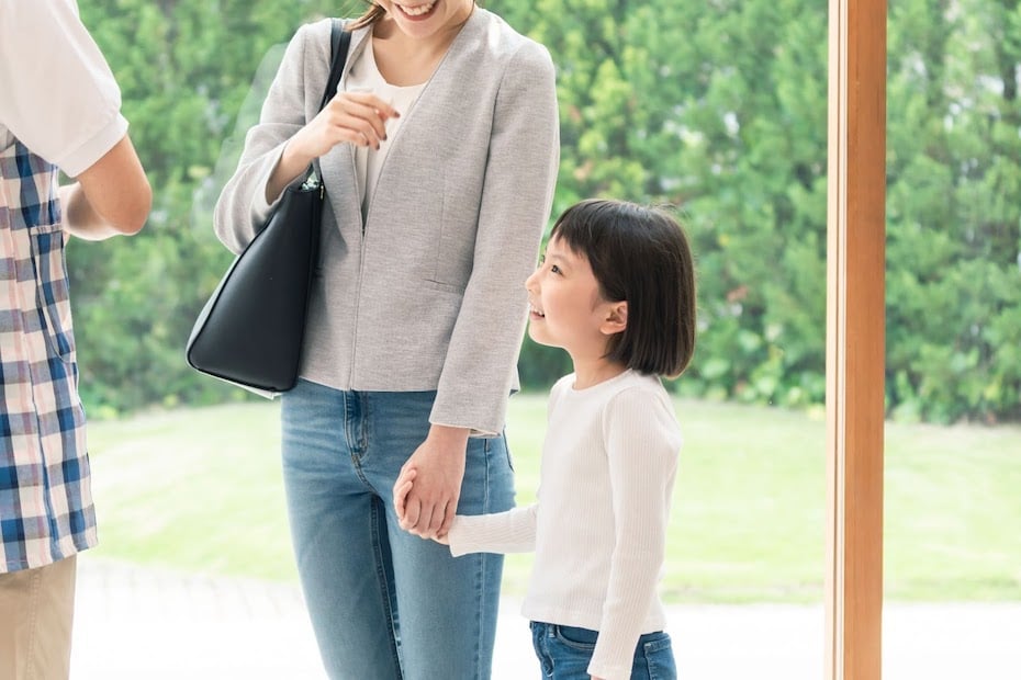 A parent holds their child's hand in support of their mental health while meeting a new student