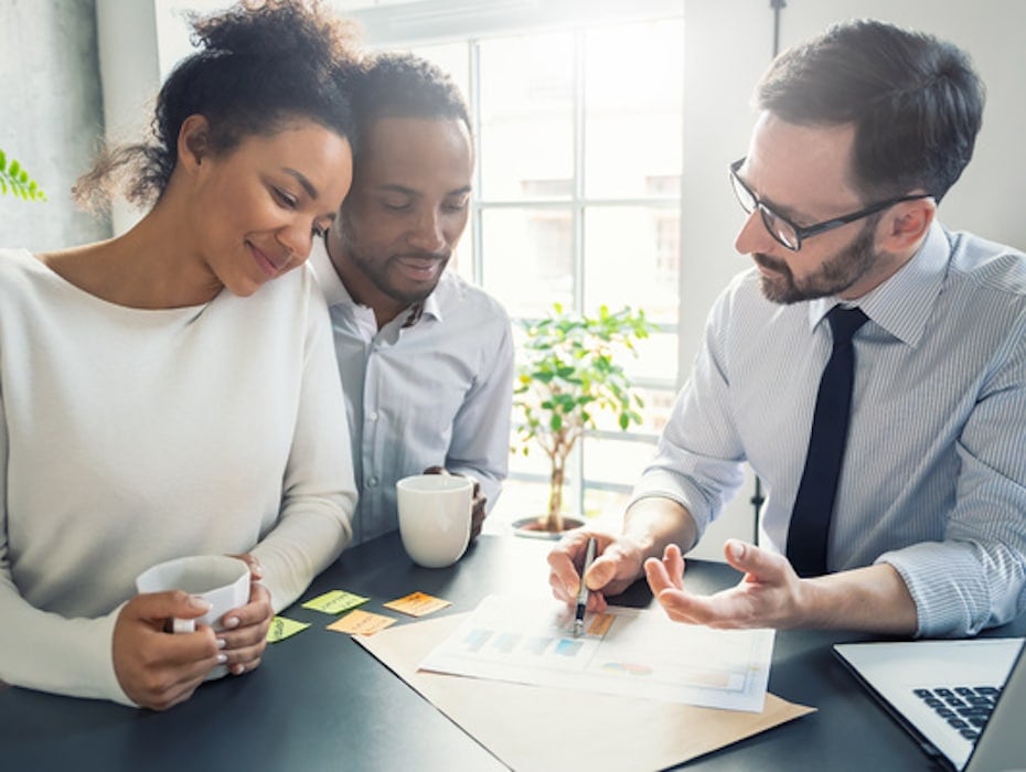 Two clients sitting at a table with a financial services employee discussing mortgages and lending during the Great Resignation.