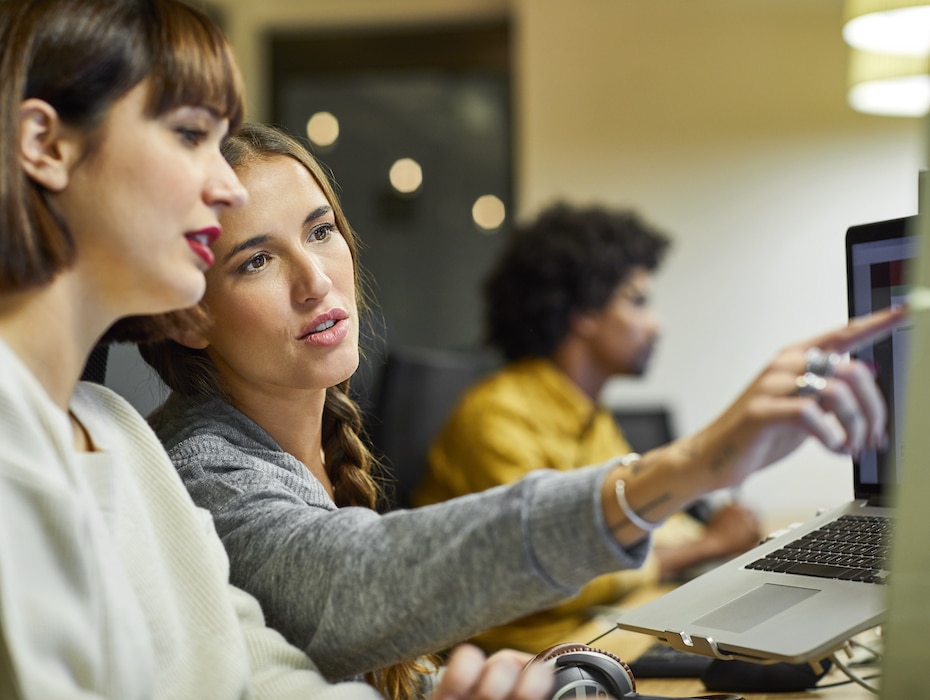 Coworkers discussing over computer in office