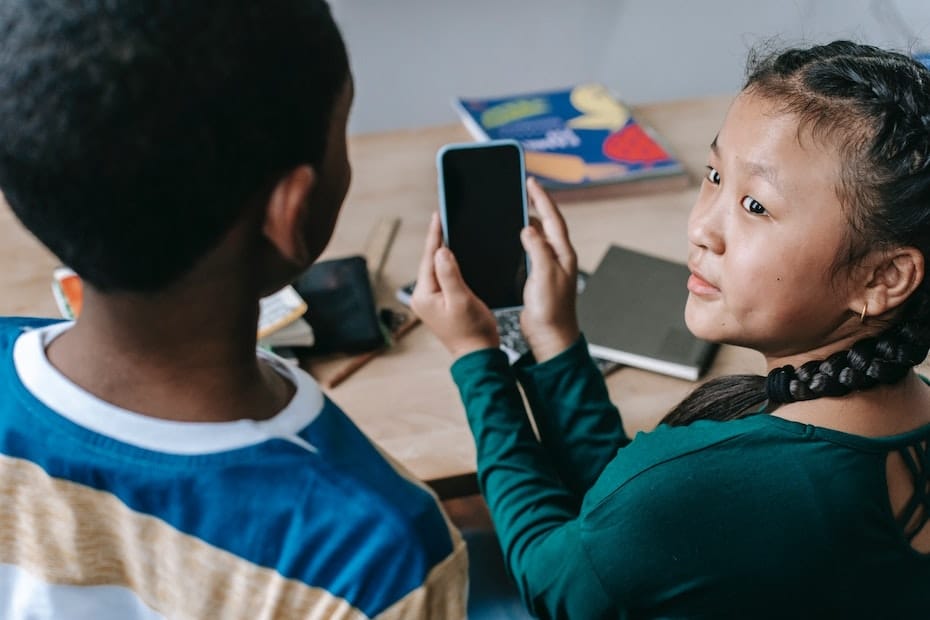 Two students interacting with each other while holding a mobile phone