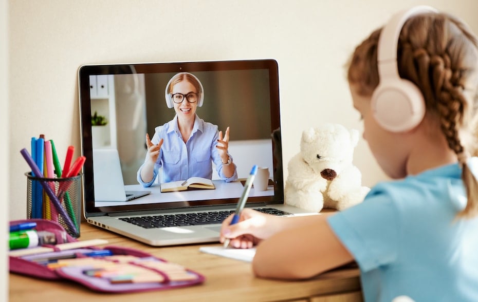 Girl listening to friendly teacher during online lesson to demonstrate the benefits of video conferencing in education