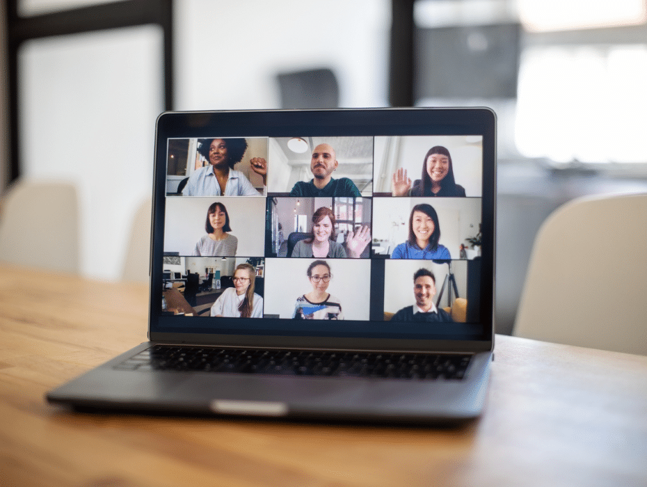 Laptop on table with multiple people in a video meeting