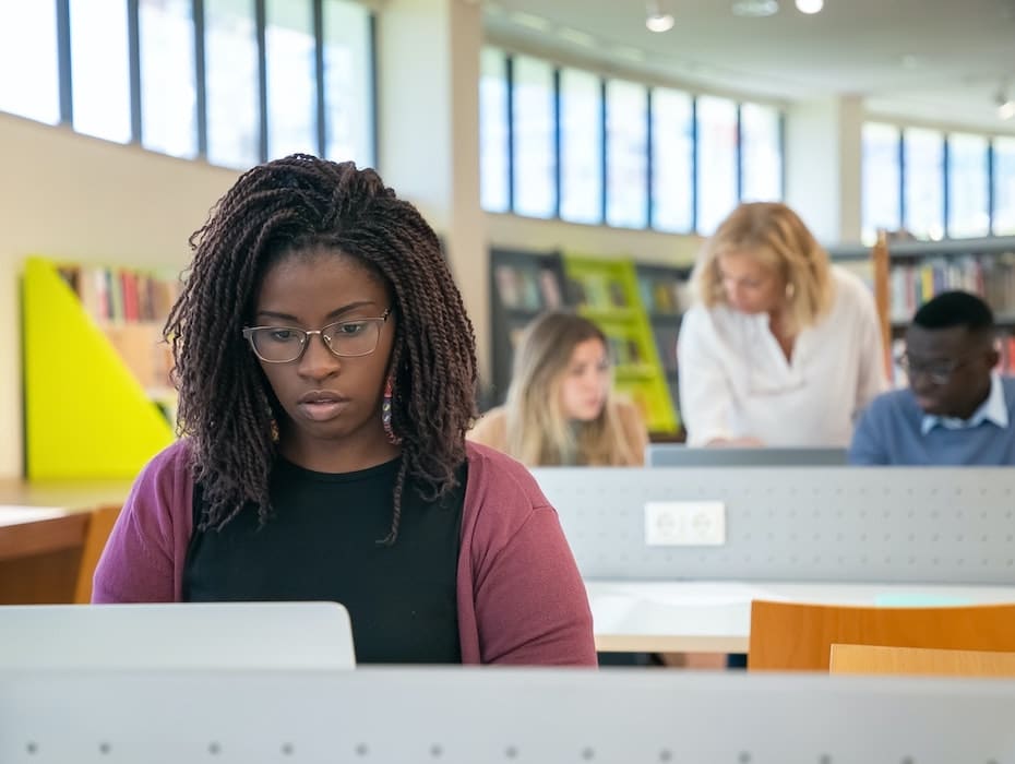 Student studies in a library setting in front of a computer