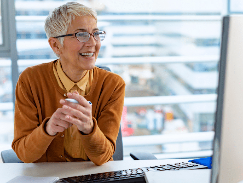 A smiling woman sits in front of her computer