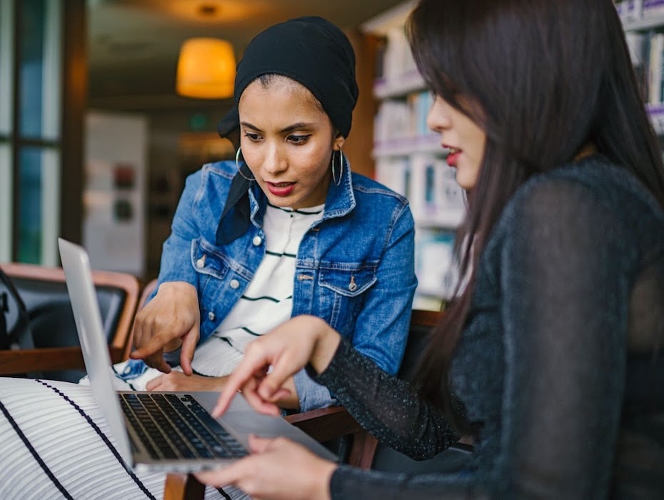 Two retail employees using a laptop to leverage their all-in-one communications solution.