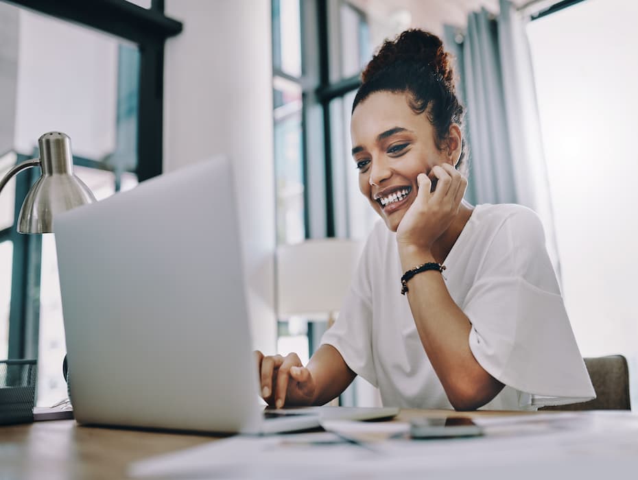 Woman smiles while looking at a computer, working from home