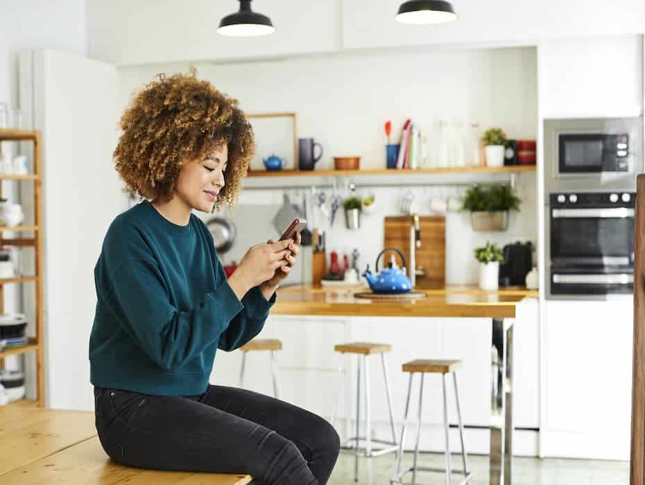 Women sits on the counter looking at her phone calling a contact center.