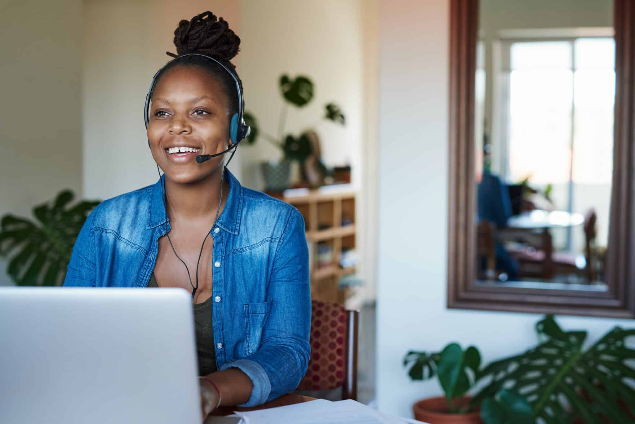 Shot of a young woman using a laptop and headset while working from home