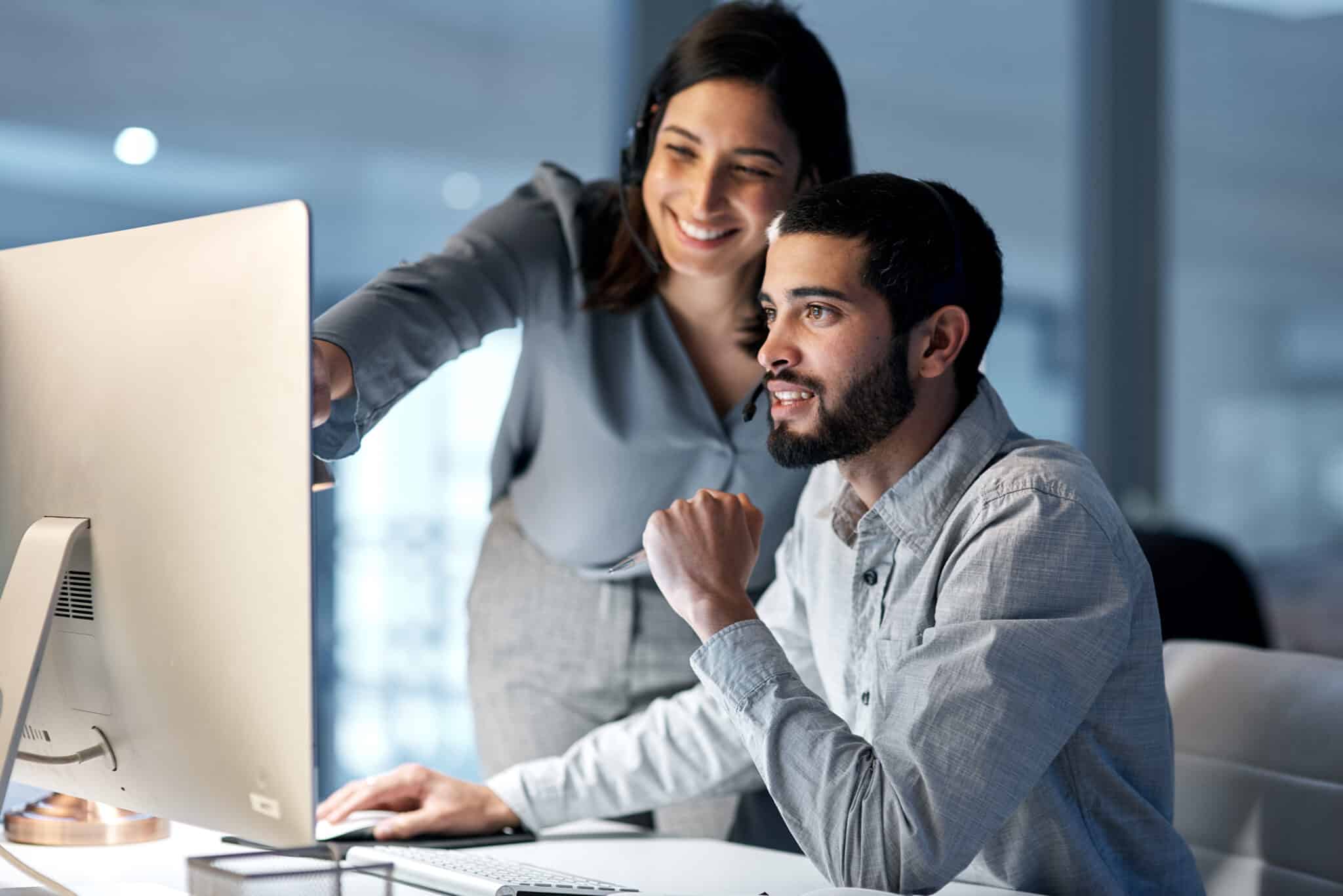 Shot of a young woman helping her colleague in a call centre late at night