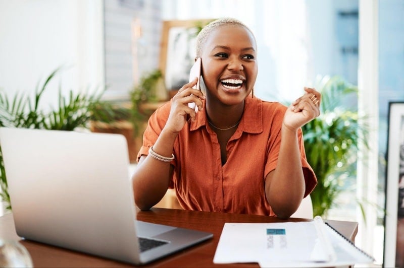 smiling professional speaking on a phone working from home