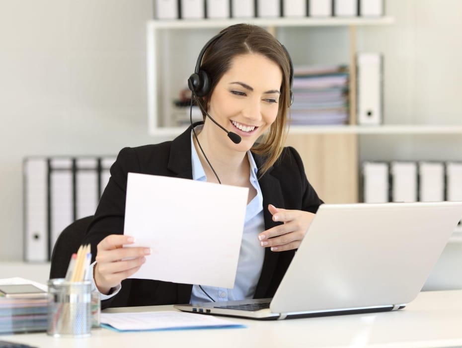 smiling woman with a headset at her desk