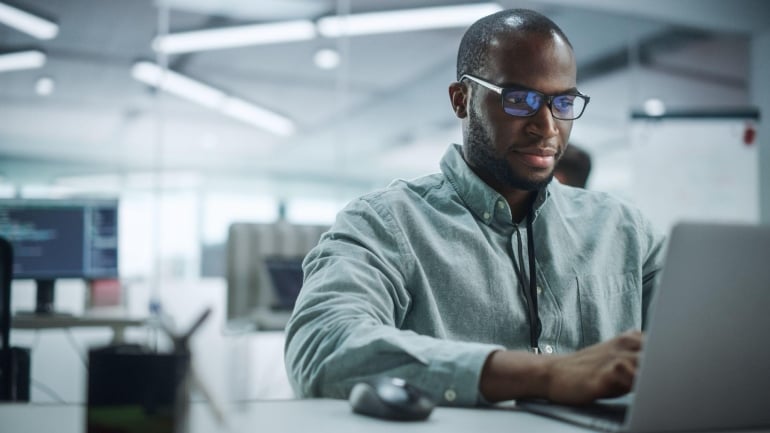 Professional working on cloud communications security on a laptop in a modern office environment